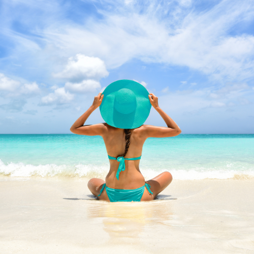 donna che guarda il mare e si tiene il cappello