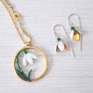 una collana con un ciondolo a cerchio con all'interno un fiore bianco e orecchini con fire bianco